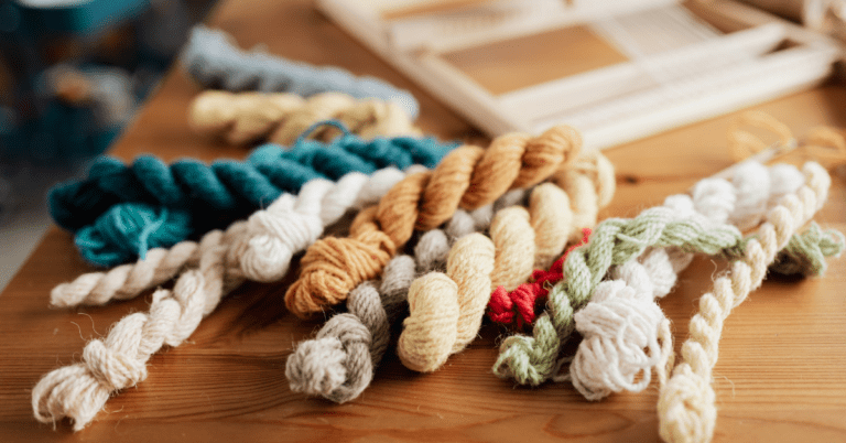 Yarn skeins of different colours laying on a wooden table